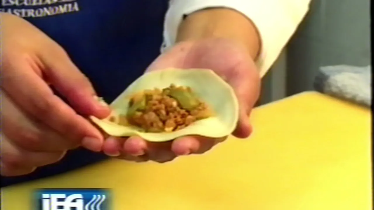 Manos de un cocinero de Escuelas de Gastronomía del Instituto IEA rellenan una empanada salteña en La Hora del Chef y algo más (Canal 26)